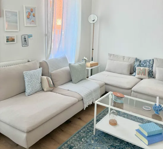 Espace de vie lumineux avec canapé modulaire et décoration murale minimaliste dans un appartement rénové.