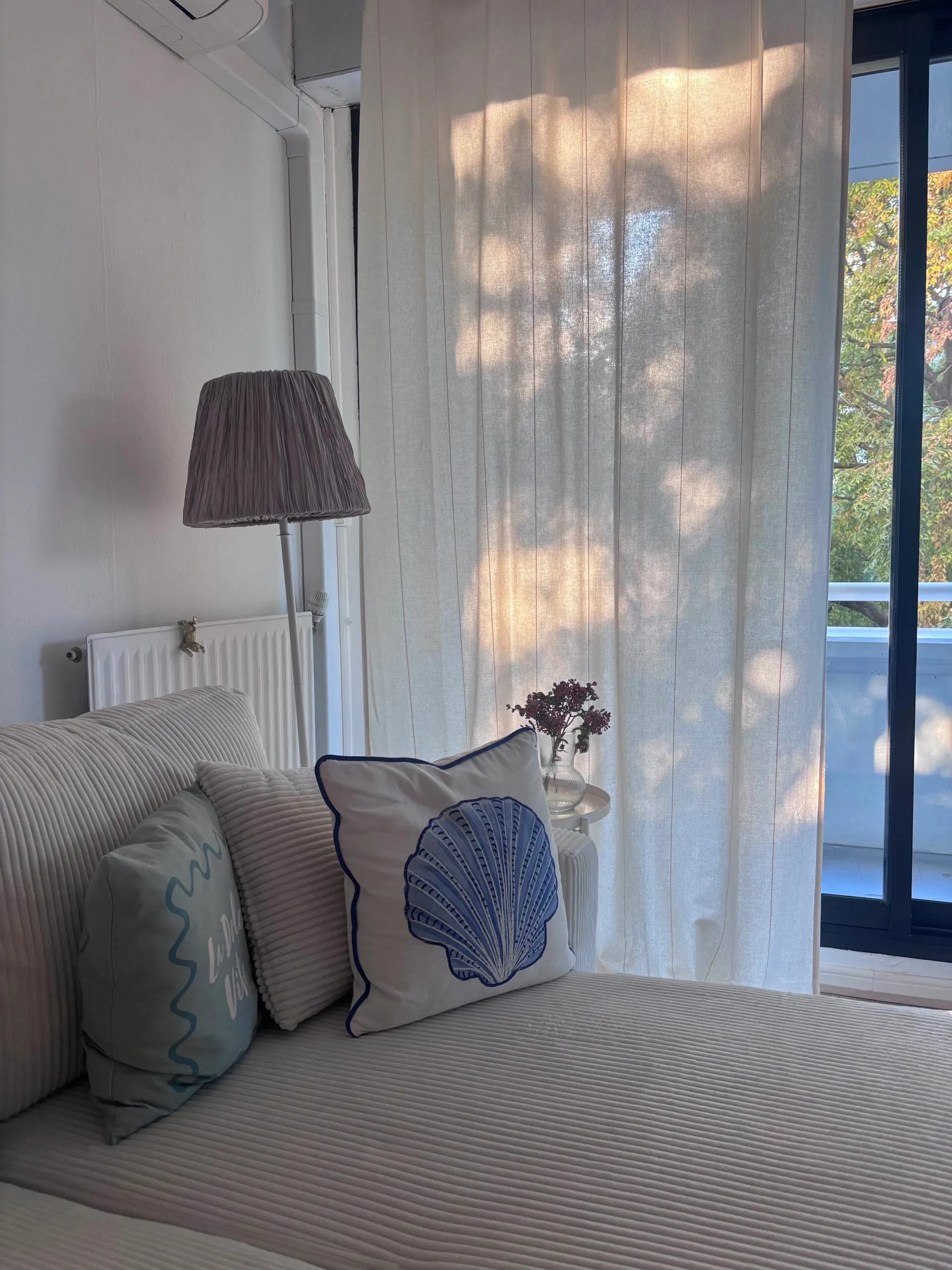 Zoom sur la décoration du salon avec luminaires sur pied et coussins aux motifs marins pour une ambiance de vacances.